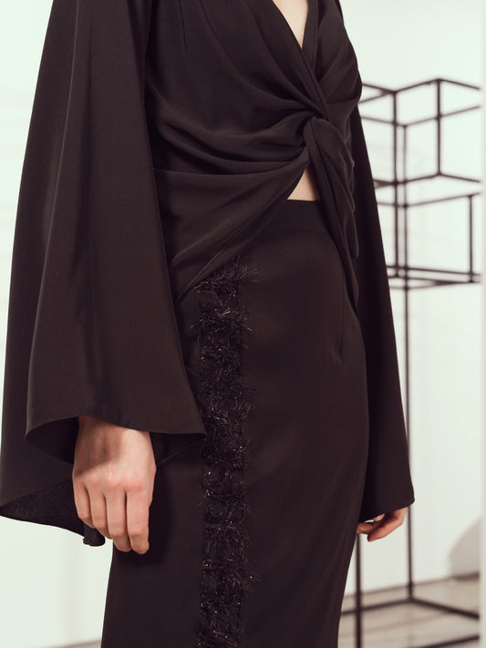 A Knotted Black Top with Flared Sleeves Paired with a Skirt with Metallic Folds